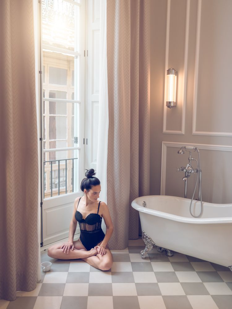 Sensual female sitting in lotus pose in bathroom