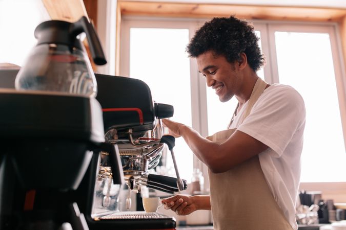 Professional barista holding cup on the coffee machine