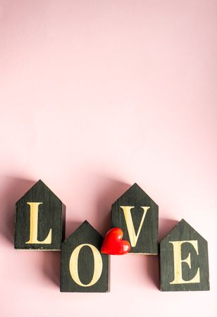 Word "love" on pink pastel table with red heart