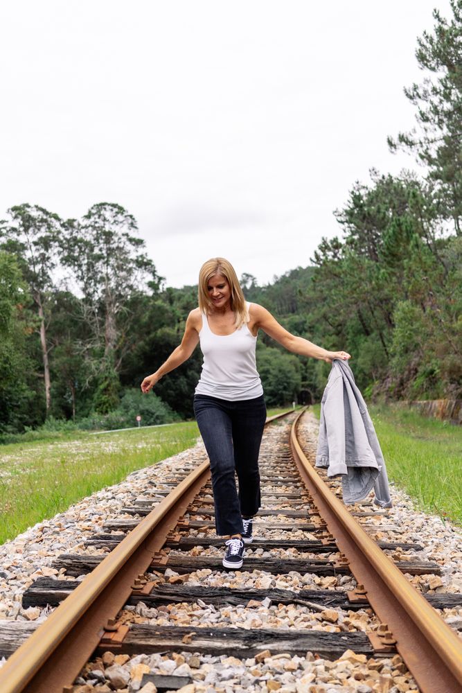 Woman walking along railway though greenery part of road