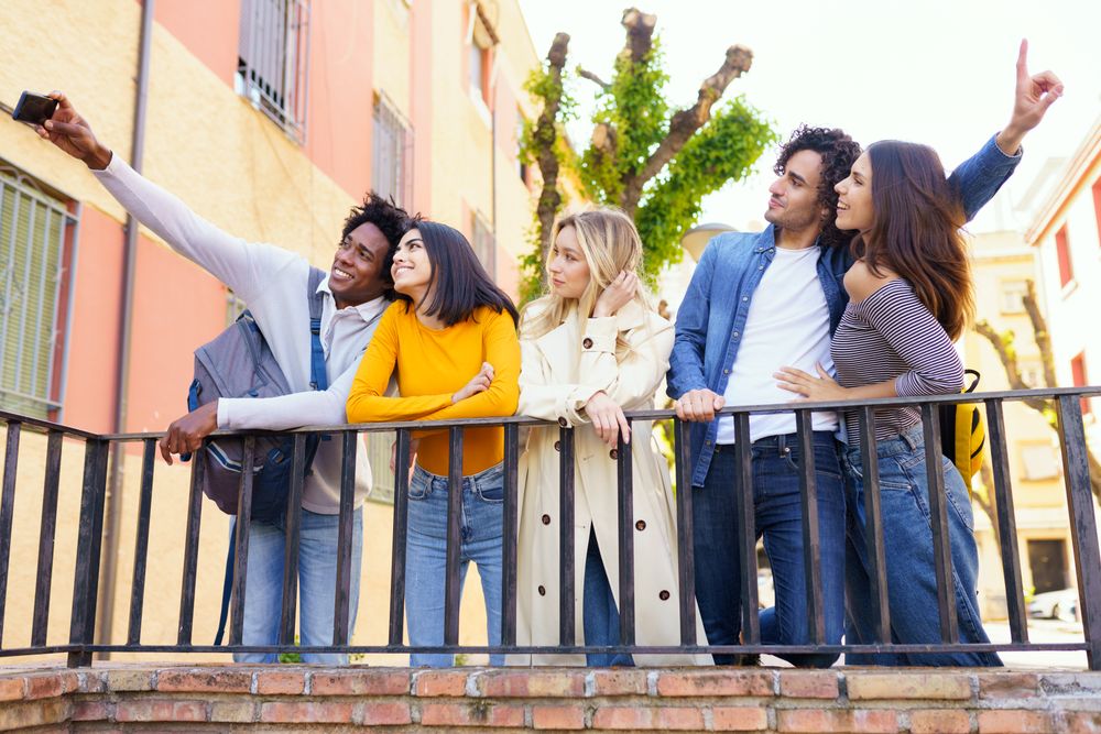 Male and female friends taking selfies together outside