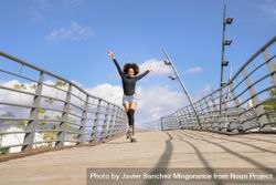 Woman with afro hairstyle in roller skates on wooden bridge with arms up 5Qwxdb