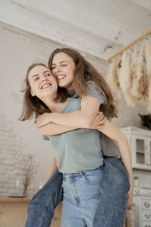 Laughing girlfriends sitting on washing machine in house
