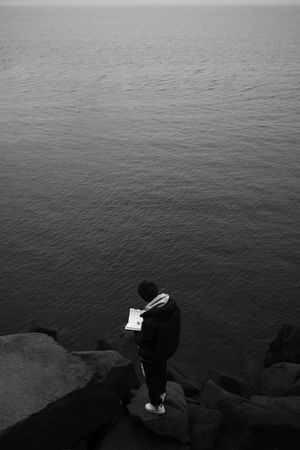 Man standing on rocky coast looking at water