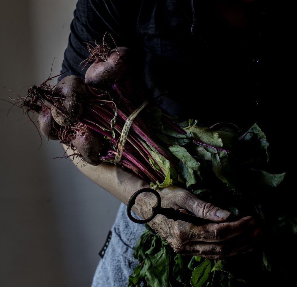 Faceless person with bunch of beetroots and key