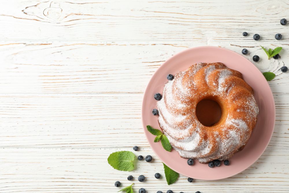 Cake with powder sugar and blueberry on wooden background, top view
