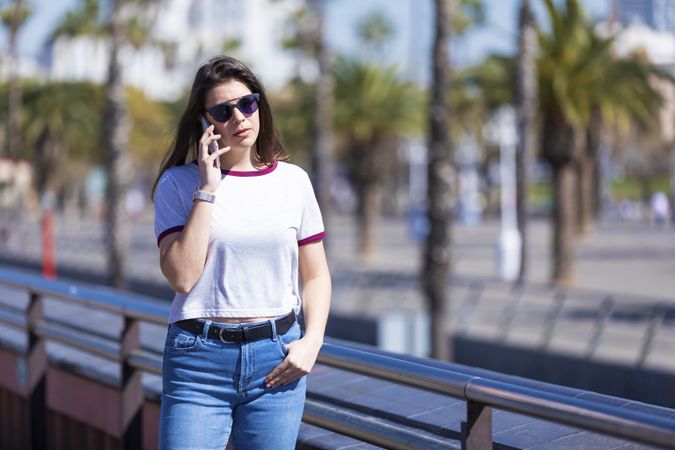 Young woman in sunglasses talking on phone on sunny day