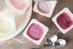Composition with plastic cups with yogurt on grey table