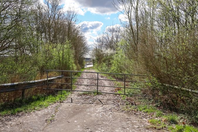 Open metal gate leading to a dirt road in the countryside