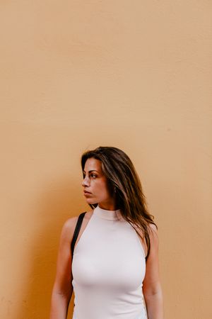 Young brunette standing against orange background
