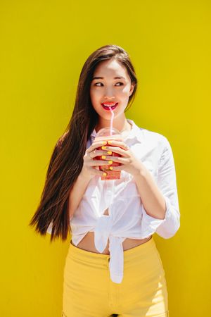 Smiling woman holding a cup of juice standing outdoors