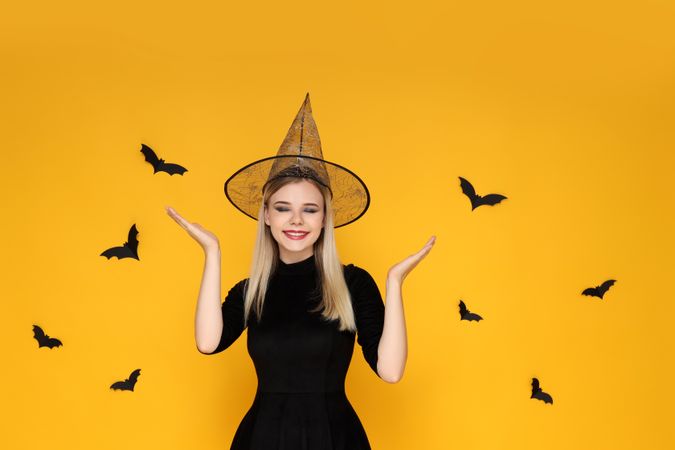 Concept of Halloween, young woman on yellow background