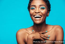Close up of smiling woman with vivid makeup against blue background 47eXB0