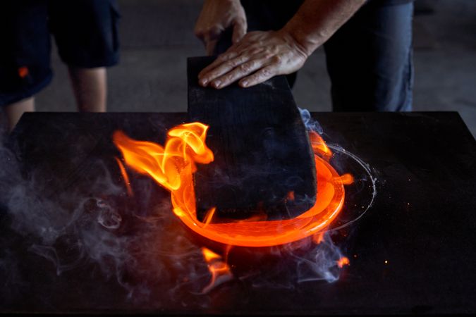Unrecognizable craftsmen making product at glassblowing factory