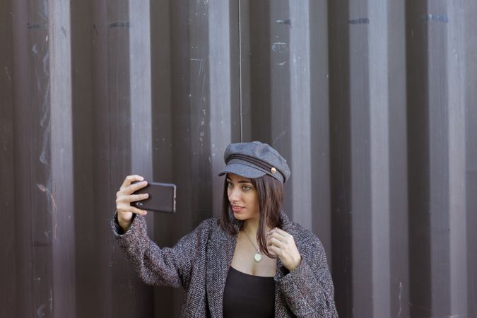Charming Hispanic lady taking selfie near wall