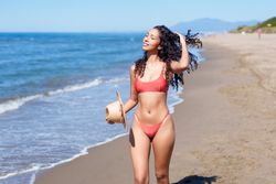 A Joyful Woman Fully Enjoying a Wonderful Day at the Beach with Her Refreshing Coconut Drink