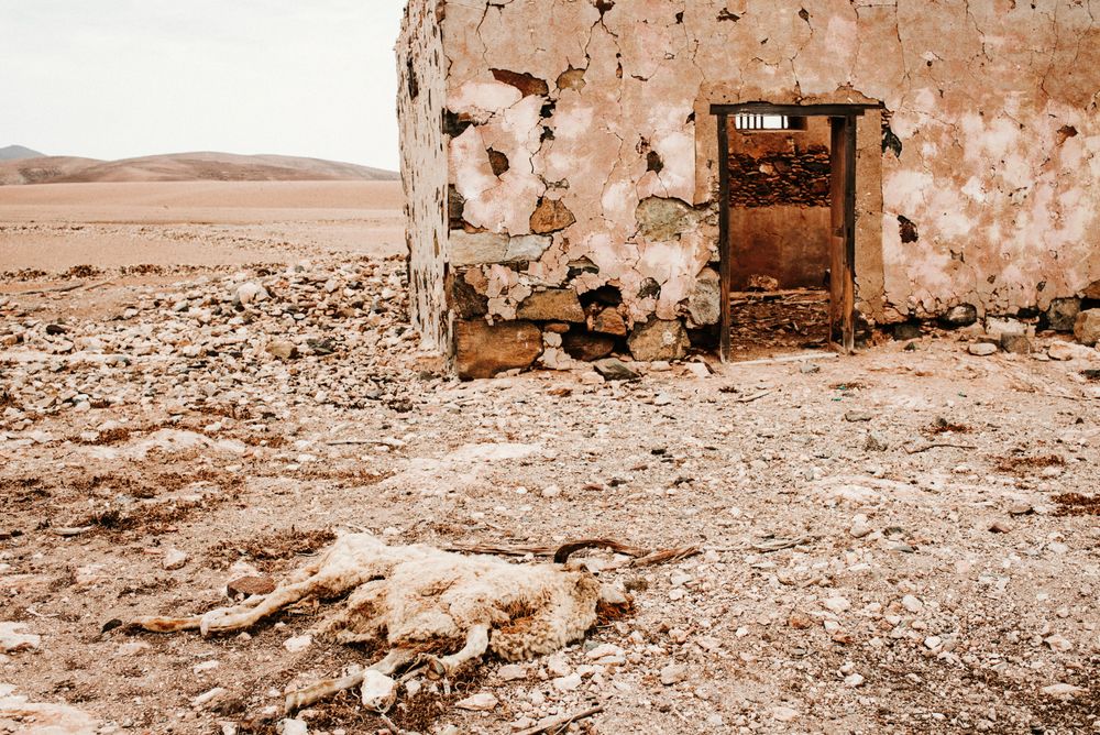 Dilapidated old buildings in mountain desert under cloudy sky