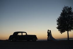 Woman and man holding hands near vintage car at sunset