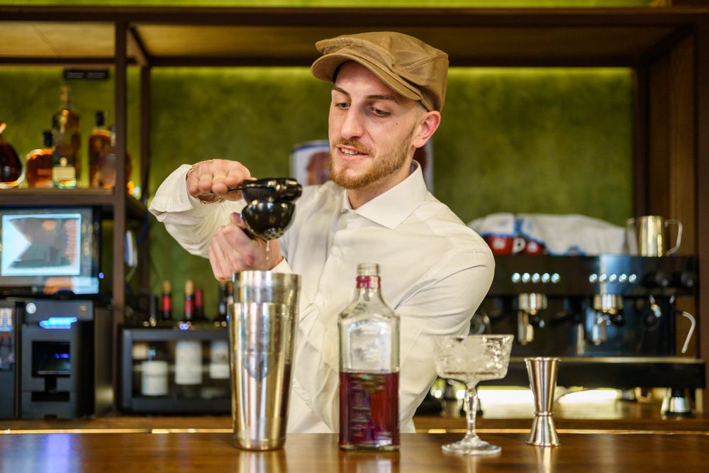 Bartender squeezing pressed juice into a shaker for cocktail