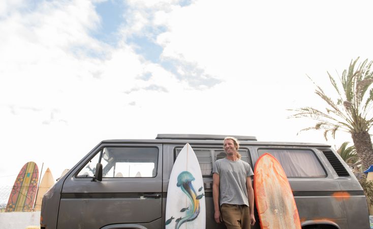 Man standing near surf boards and van
