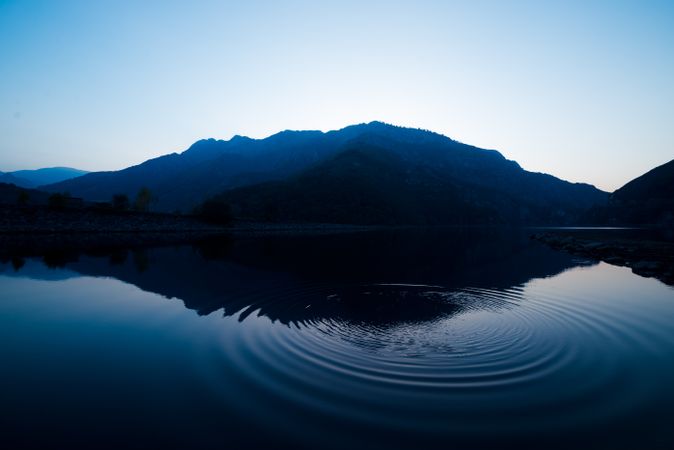 Picturesque view of water surface near amazing rock hills at sunset and blue sky