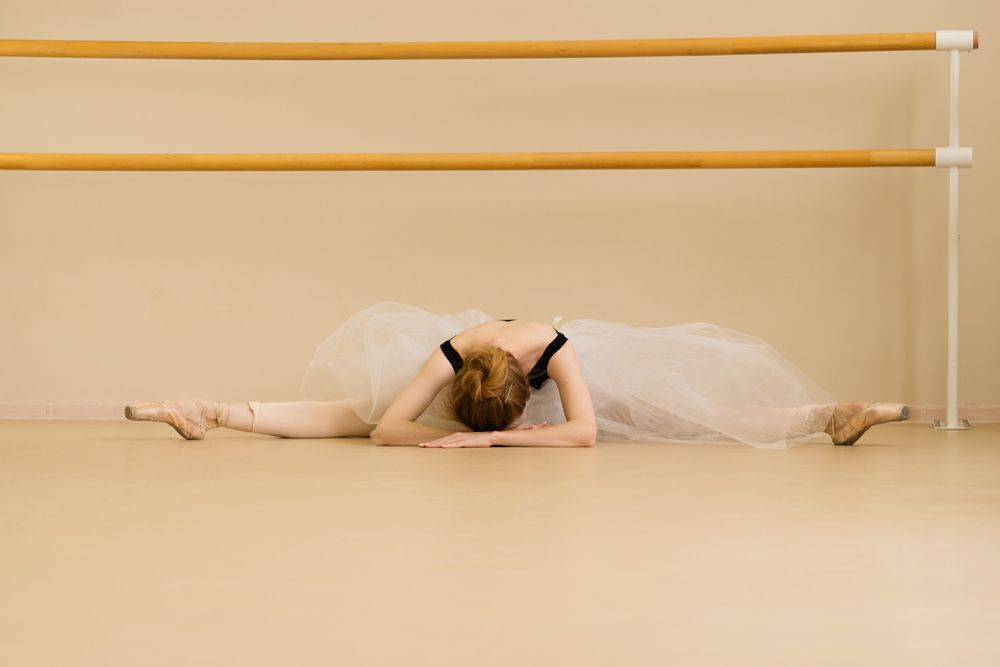 Ballet dancer stretches forward on the studio floor