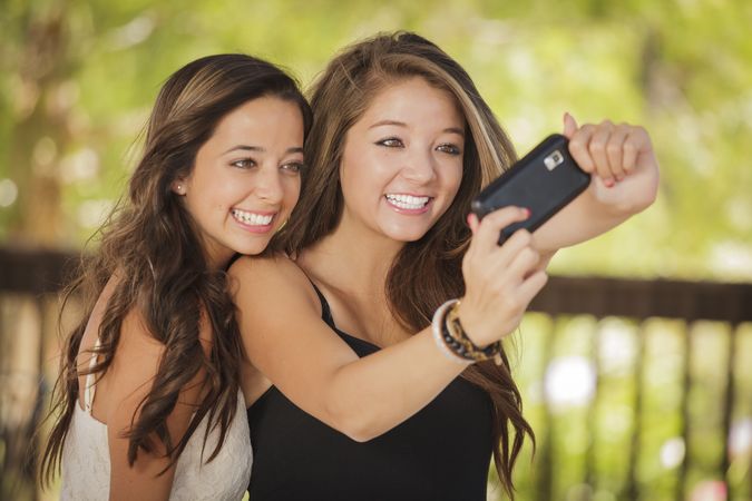 Two smiling female friends taking selfie in outside garden