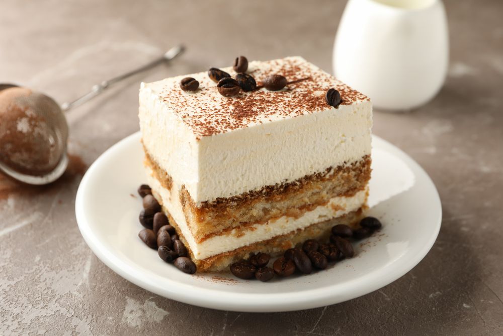 Composition with plate of tiramisu on light brown background. Tasty dessert