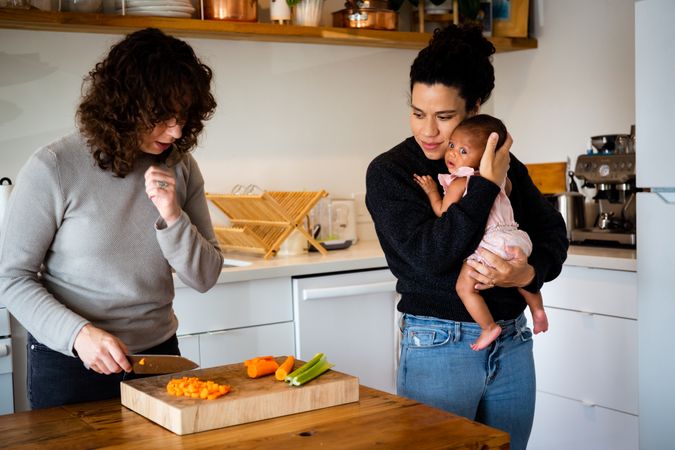 Woman holding baby while partner prepares food