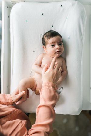 Crop mother playing with newborn baby boy