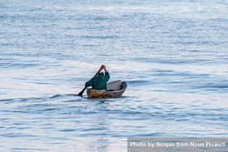 Man in green shirt paddling in the middle of the ocean beBOP0