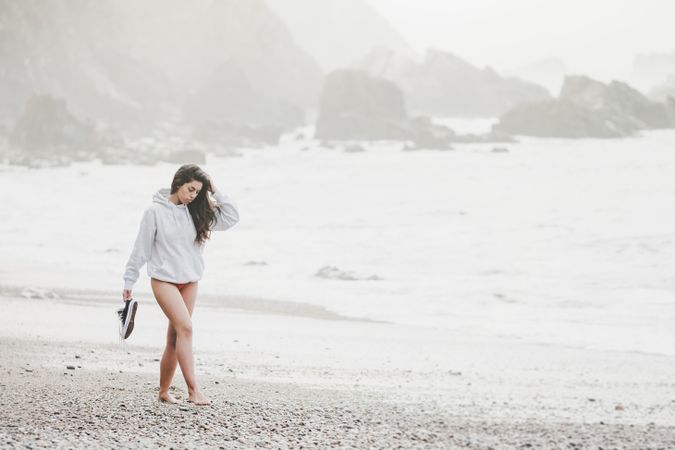 Woman walking on shore near stones and water