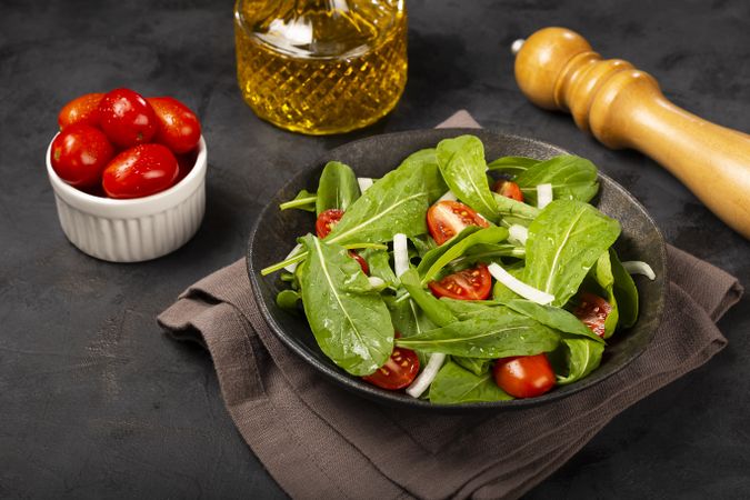 Arugula salad with tomatoes on dark background.