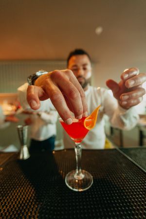 Cheerful man preparing a cocktail in a bar.