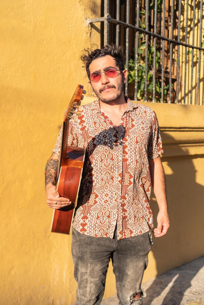 Latin musician standing in the street holding his guitar