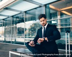Young businessman waiting and checking time with mobile phone 4Z2Qx4