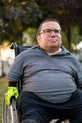 Portrait of proud man sitting in wheelchair under tree, portrait