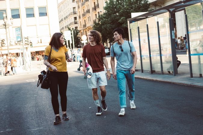Cheerful multiracial friends hugging and walking along city street