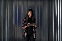 Cheerful woman browsing tablet near storage