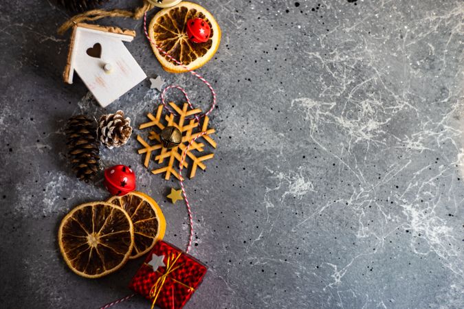 Top view of wooden snowflakes, bird house, dried orange slices and pine cones on marble table