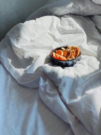 Duvet in morning light with bowl of orange slices