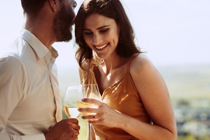 Close up of a smiling couple standing together holding wine