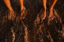 Crop legs near waving sea water
