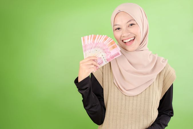 Happy Asian Muslim Woman Holding Rupiah