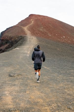 Back of man jogging up hill