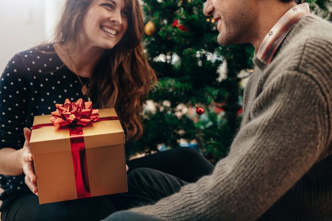 Happy couple exchanging Christmas gifts in their living room