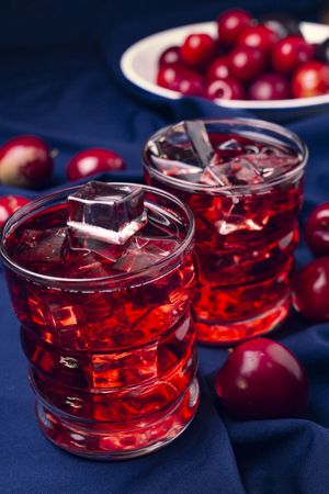 Red beverage near fresh fruits on cloth