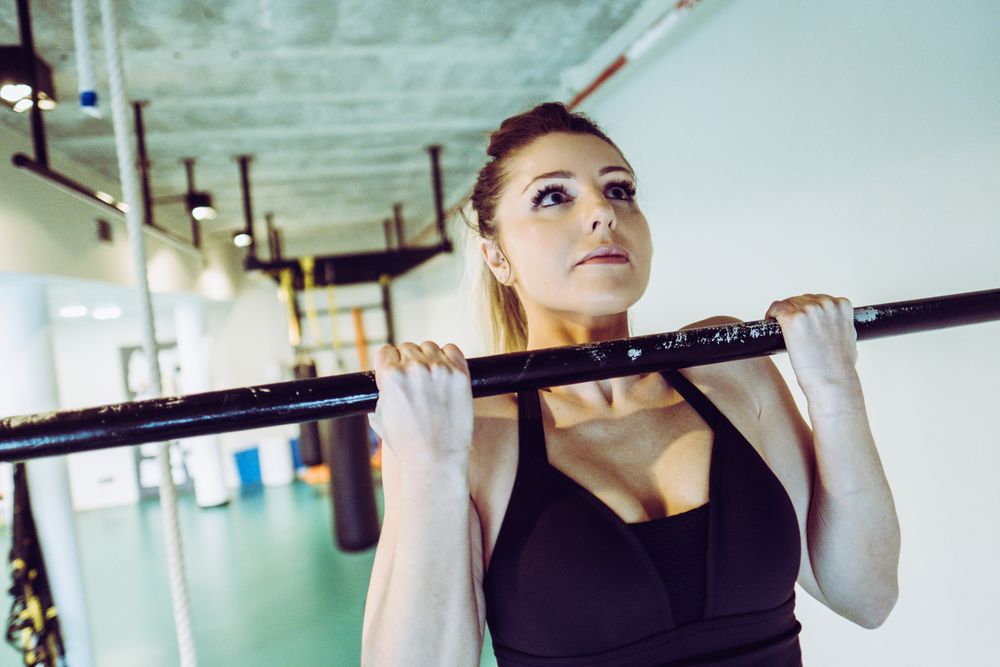 Young woman doing pull ups in gym