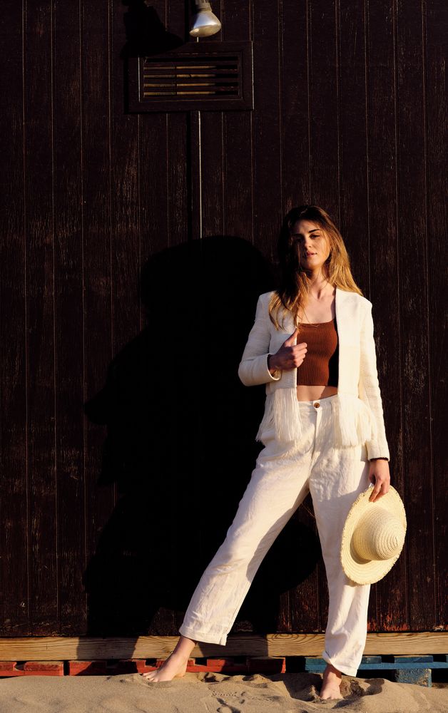 A long hair fashion model with a hat at the beach with a dark background