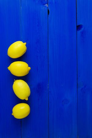 Four lemons stacked on the left on wood painted blue